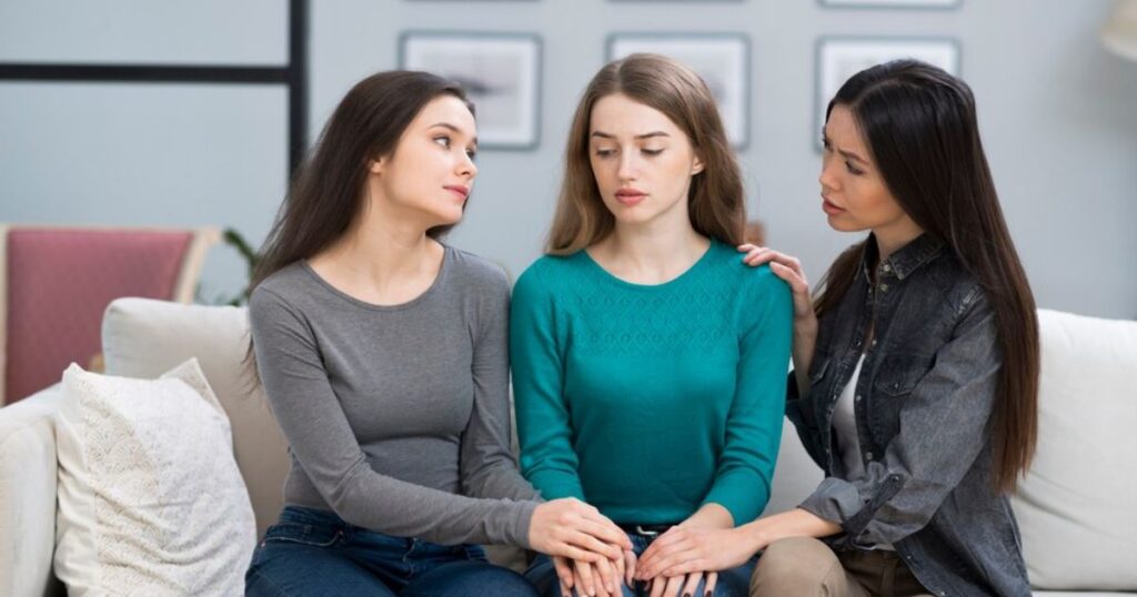 Three women sitting together on a couch showing emotional support, representing the importance of taking a bipolar disorder test for women.